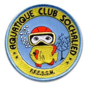 Ecusson rond brodé du club aquatique sochalien. Il représente un petit plongeur, en combinaison jaune avec un bonnet orange et un masque qui fait des bulles dans une eau bleue. Autour, un bandeau jaune faisant le tour de l'écusson, sur lequel il est écrit Aquatique club sochalien, FFESSM.